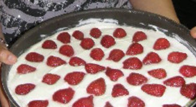 1 пакет Какаови бисквитки
2-3 лъжици разтопен мед
400 г Цедено кисело мляко
250 г Заквасена сметана
1 лимон
100 г Печени лешници
1 чаша захар
1/2 кг ягоди