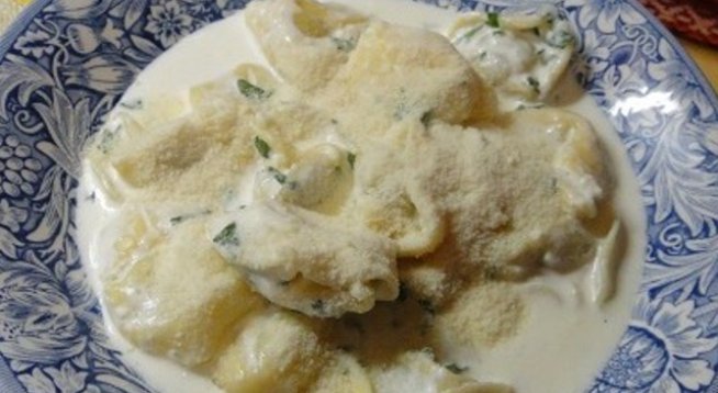 250 г равиоли пресни
150 мл готварска сметана
50 г пармезан настърган
сол на вкус
няколко стръка магданоз