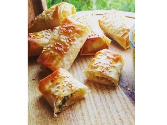 1 пакет кори за баница
400 г козе сирене
4 картофа
1 скилидка чесън
1/2 връзка магданоз
черен пипер, сол
4 яйца
100 г кисело мляко
1 с. л. зехтин
сусам за поръсване