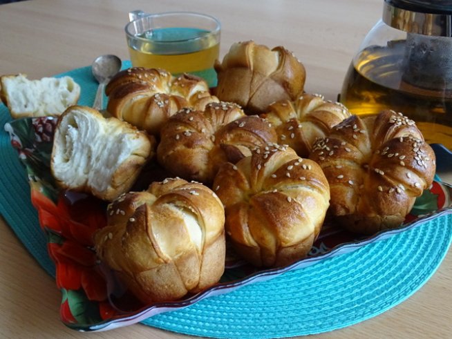 200 г крема сирене (Lacrima) 
1 яйце + 1 жълтък за намазване 
200 мл прясно мляко
500 г бяло брашно
1 пакетче суха мая 
100 мл олио
1 ч. л. захар 
1 ч.л. сол 
сусам 
1 ч. л. заквасена сметана 
