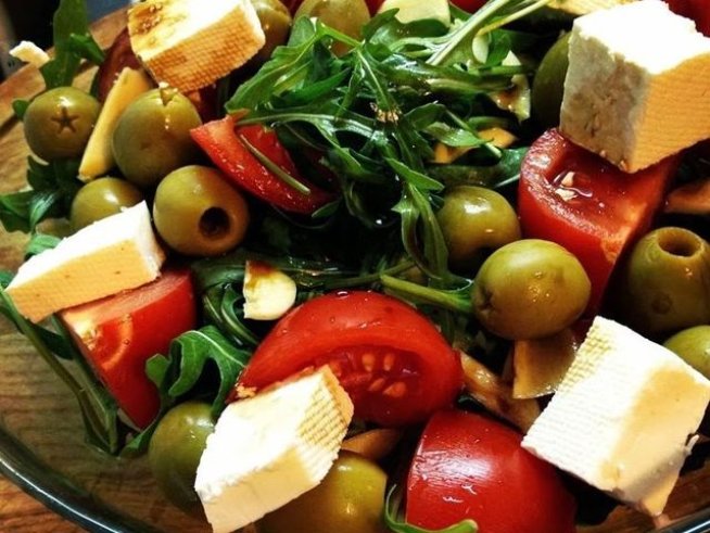 200 г рукола 
100 г бяло краве сирене 
2 домата
3 скилидки чесън
маслини без костилки 
сол
зехтин
соев сос с аромат на чесън или обикновен
