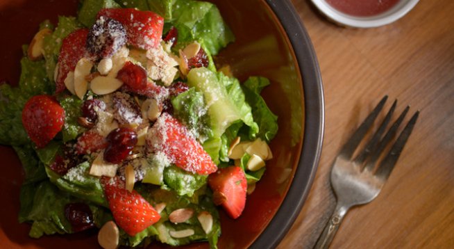 1 маруля, накъсана 
100 г ягоди, нарязани 
100 г семена от нар
50 г филиран бадем
пармезан за поръсване 
сол и черен пипер на вкус
1 супена лъжица оцет балсамико
1 супена лъжица зехтин 