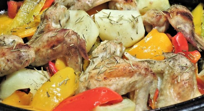 4-5 пилешки бутчета или 10 крилца
1 голямо кубче масло
4-5 супени лъжици олио
2 глави лук
2 скилидки чесън
2 печени чушки от буркан
3 домата
2 картофа
1 шепа маслини
1 морков
риган
сол
черен пипер
червен пипер
½ чаша бяло вино
