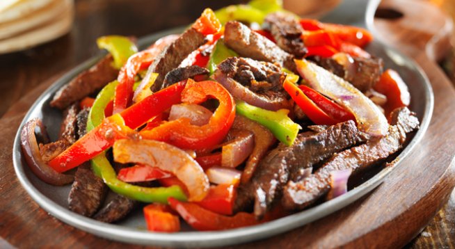 1 кг телешко филе
чесън на гранули на вкус
3 супени лъжици олио
1 кубче телешки бульон
¼ чаша гореща вода
1 супена лъжица царевично нишесте
½ чаша нарязан лук
2 големи зелени чушки, нарязани на едри жулиени
2 големи червени чушки, нарязани на едри жулиени
1 консерва домати, белени
3 супени лъжици соев сос
1 чаена лъжица захар
1 чаена лъжица сол
