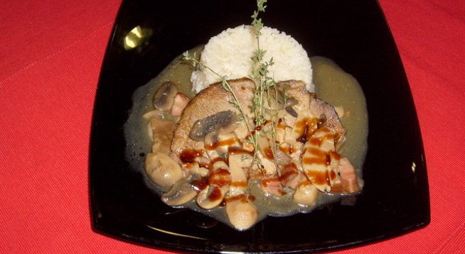 1,200 кг свински врат без кост
500 г манатарки
300 г пушен бекон
сол, черен пипер
200 мл червено вино
1 глава лук
4 скилидки чесън
1 супена лъжица брашно
ориз за гарнитура
100 г масло