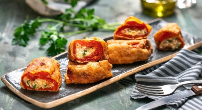 2 буркана печени червени чушки 
250 г краве сирене
50 г кашкавал
1 обелен домат
1/4 връзка магданоз
2 с.л. галета
4 яйца
1/2 ч.л. сух чесън
брашно за овалване
олио за пържене на маслена баня