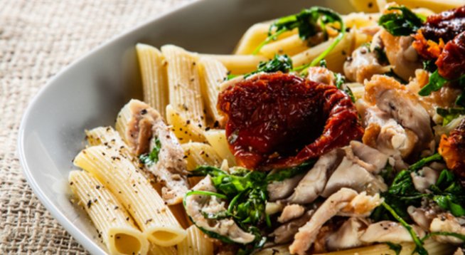 400 г пилешки гърди без кожа
300 г паста penne
зехтин
1/4 чаша сушени домати, отцедени от мазнината и нарязани
1/4 ч. л. лют червен пипер, по желание
200 г пресни печурки
3 скилидки стрит чесън
1 бурканче босилеково песто
1 чаша прясно мляко
сол, черен пипер на вкус