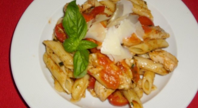 1 пакет къса паста
300 г шунка
150 г кашкавал
10 кисели краставички
супена лъжица песто
1 глава лук
8 скилидки чесън
сол, черен пипер
2-3 консерви пасирани домати или една и половина пресни
