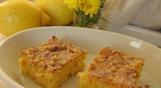 Кората от 1 лимон
2 моркова
1 ябълка
100 г масло
1 ч. ч. захар
1 ч. ч. бяло брашно
1 ч. ч. царевично брашно
3 яйца
3 суп. лъж. сметана
1 бакпулвер
1 и 1/2 пакетче ванилия
2 суп. лъж. пудра захар
1/2 ч. ч. настъргани орехови ядки