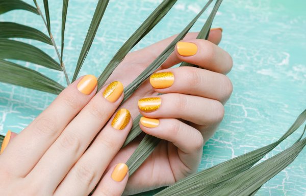 Жълт маникюр със златен брокат. Снимка: istock