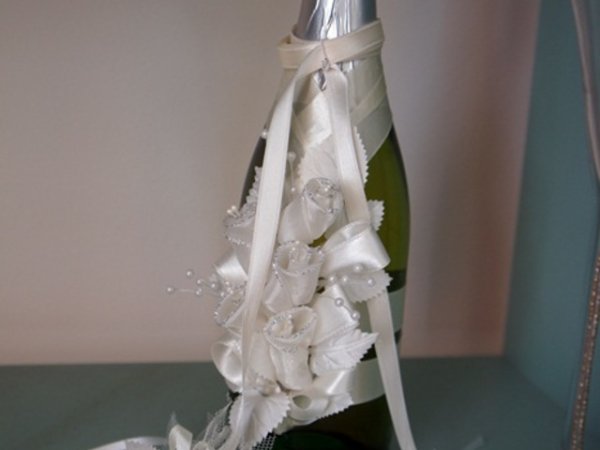Сватбено шампанско с пищна бяла украса.