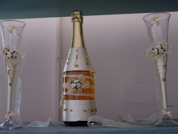 Шампанско в златно и бяло - увито с копринени конци, сатенена панделка, декоративни орнаменти и малки цветя.