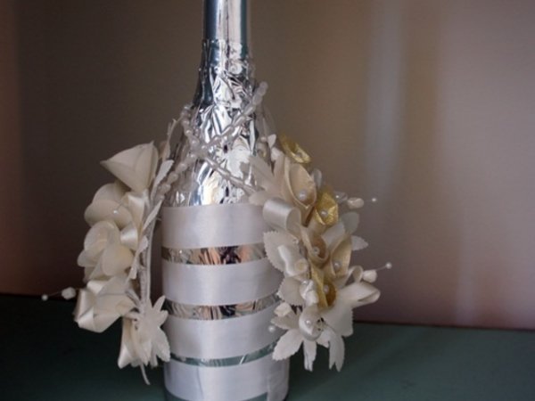 Сребърно фолио, бяла сатенена панделка и изкуствени цветя - класическо сватбено шампаско