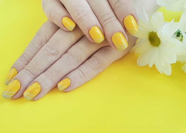 Маникюр в жълто и брокат. Снимка: istock